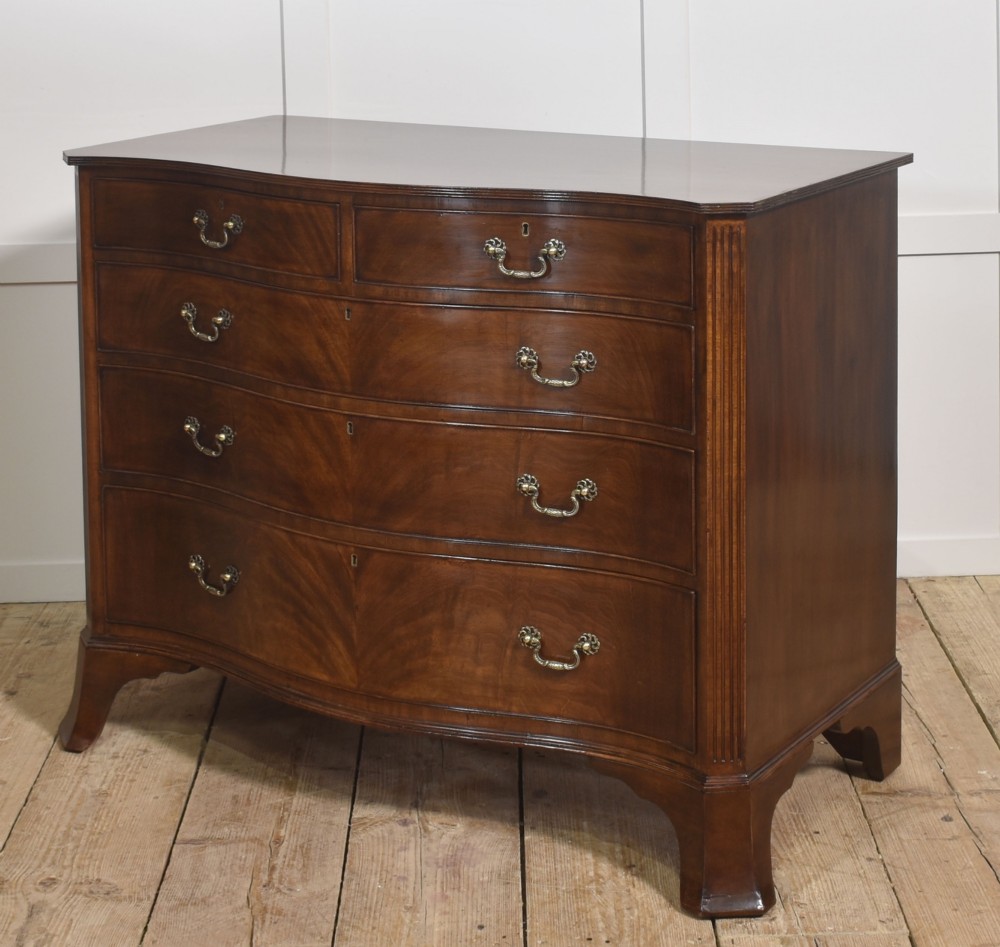 An Edwardian figured mahogany bow front chest of drawers featuring two short over three long drawers with brass swan-neck handles and splayed bracket feet. View VIII
