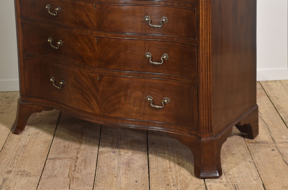 An Edwardian figured mahogany bow front chest of drawers featuring two short over three long drawers with brass swan-neck handles and splayed bracket feet. View IX