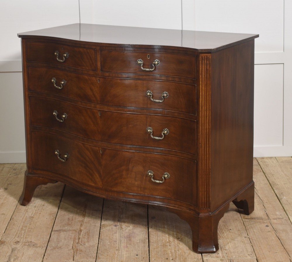 An Edwardian figured mahogany bow front chest of drawers featuring two short over three long drawers with brass swan-neck handles and splayed bracket feet. View X