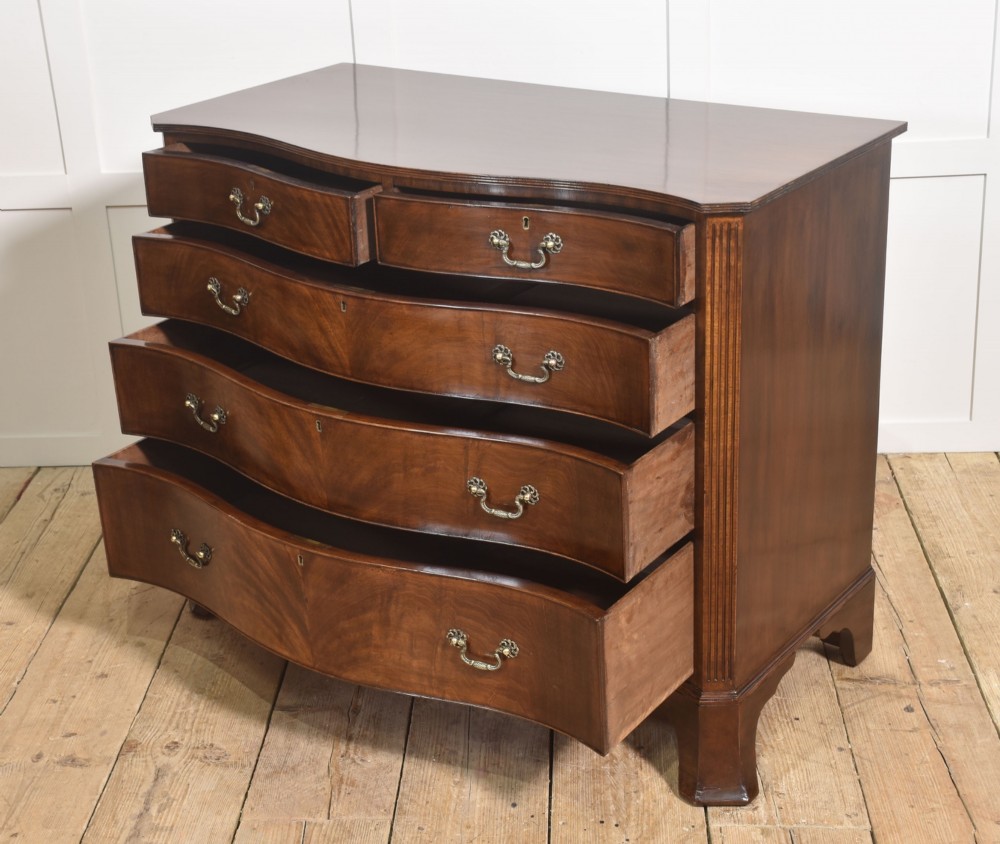 An Edwardian figured mahogany bow front chest of drawers featuring two short over three long drawers with brass swan-neck handles and splayed bracket feet. View XI