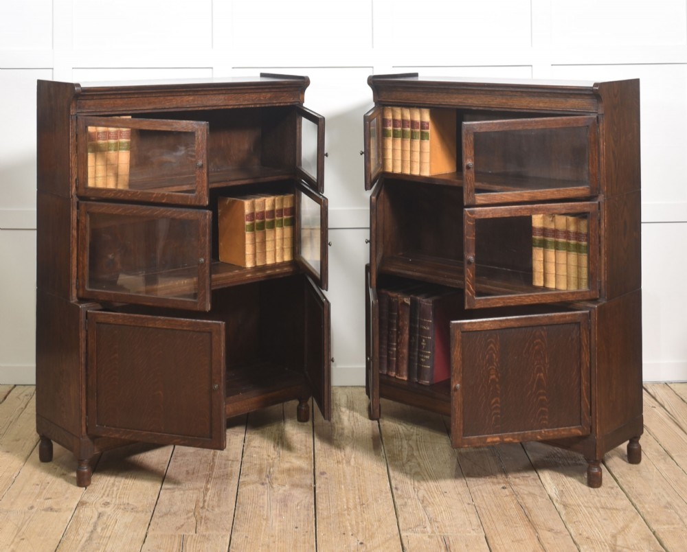 A pair of early twentieth-century dark oak sectional bookcases featuring two glazed upper tiers and a double-door base cupboard on turned feet. View IV
