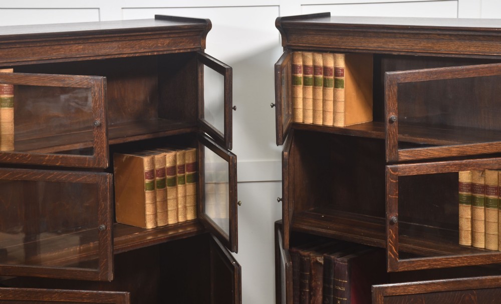 A pair of early twentieth-century dark oak sectional bookcases featuring two glazed upper tiers and a double-door base cupboard on turned feet. View V