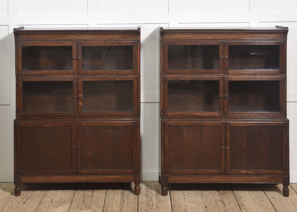 A pair of early twentieth-century dark oak sectional bookcases featuring two glazed upper tiers and a double-door base cupboard on turned feet. View VI