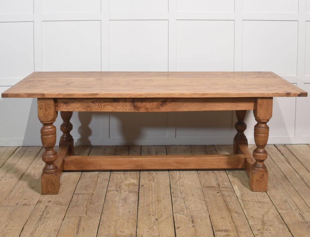 A 19th-century rectangular elm refectory dining table featuring turned wooden legs connected by a central lower stretcher. View IV