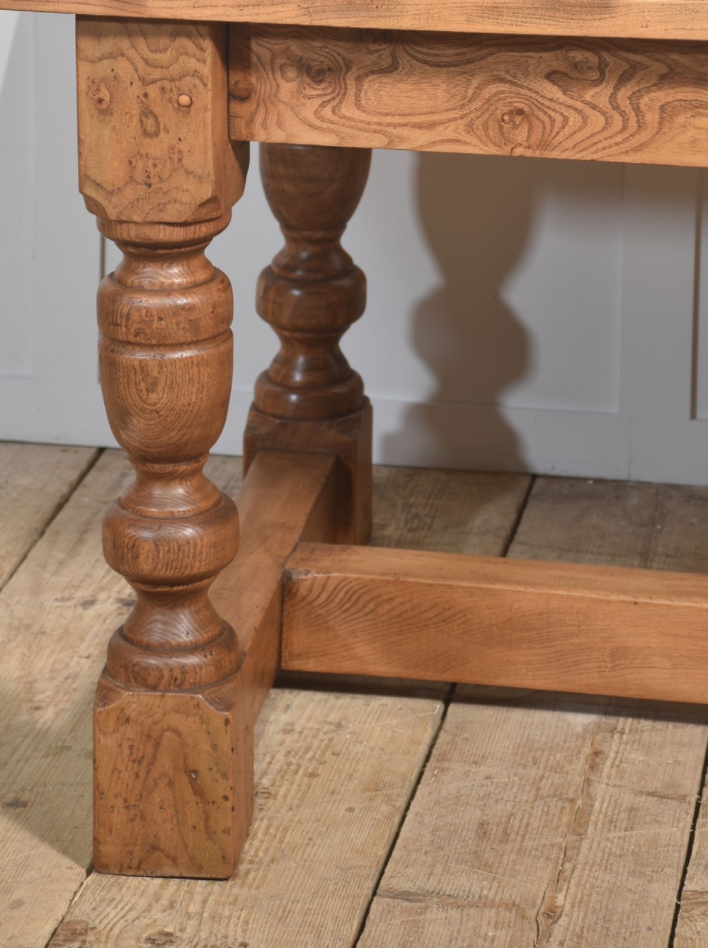 A 19th-century rectangular elm refectory dining table featuring turned wooden legs connected by a central lower stretcher. View V