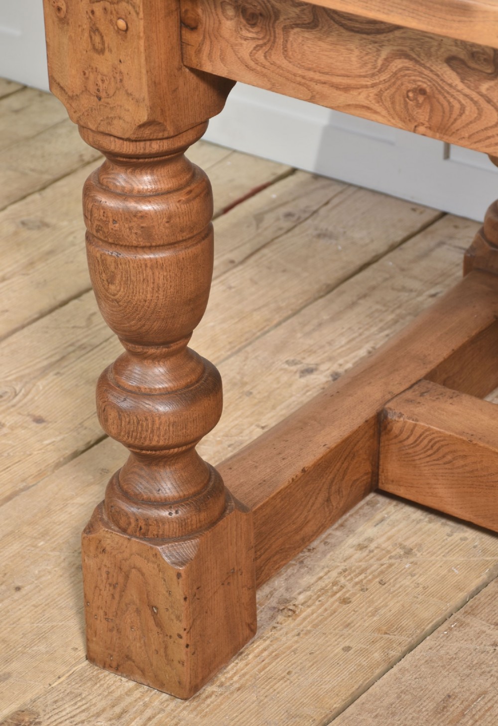 A 19th-century rectangular elm refectory dining table featuring turned wooden legs connected by a central lower stretcher. View VII