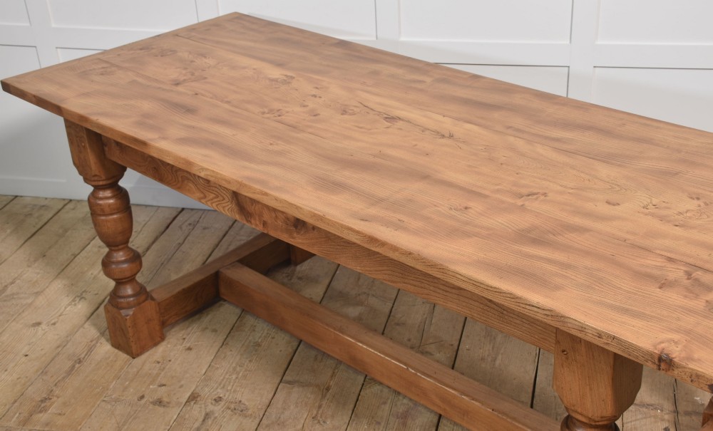 A 19th-century rectangular elm refectory dining table featuring turned wooden legs connected by a central lower stretcher. View IX