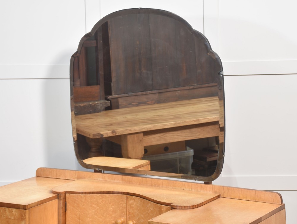 An Art Deco light blonde birds eye maple dressing table featuring curved pedestal drawers, a central cupboard, and a large shaped mirror attached above. View V