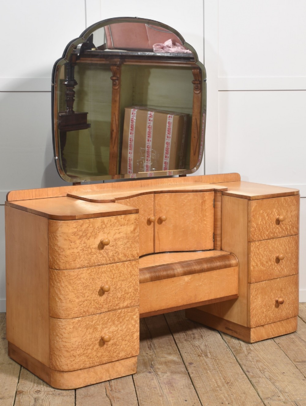 An Art Deco light blonde birds eye maple dressing table featuring curved pedestal drawers, a central cupboard, and a large shaped mirror attached above. View VII