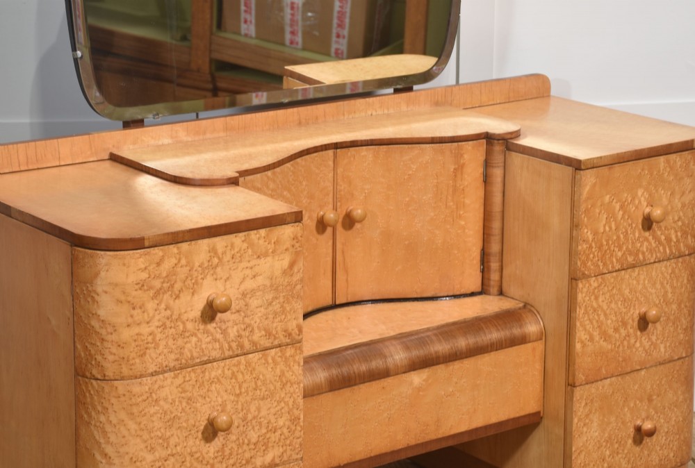 An Art Deco light blonde birds eye maple dressing table featuring curved pedestal drawers, a central cupboard, and a large shaped mirror attached above. View VIII