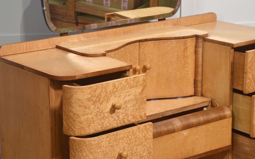An Art Deco light blonde birds eye maple dressing table featuring curved pedestal drawers, a central cupboard, and a large shaped mirror attached above. View XI