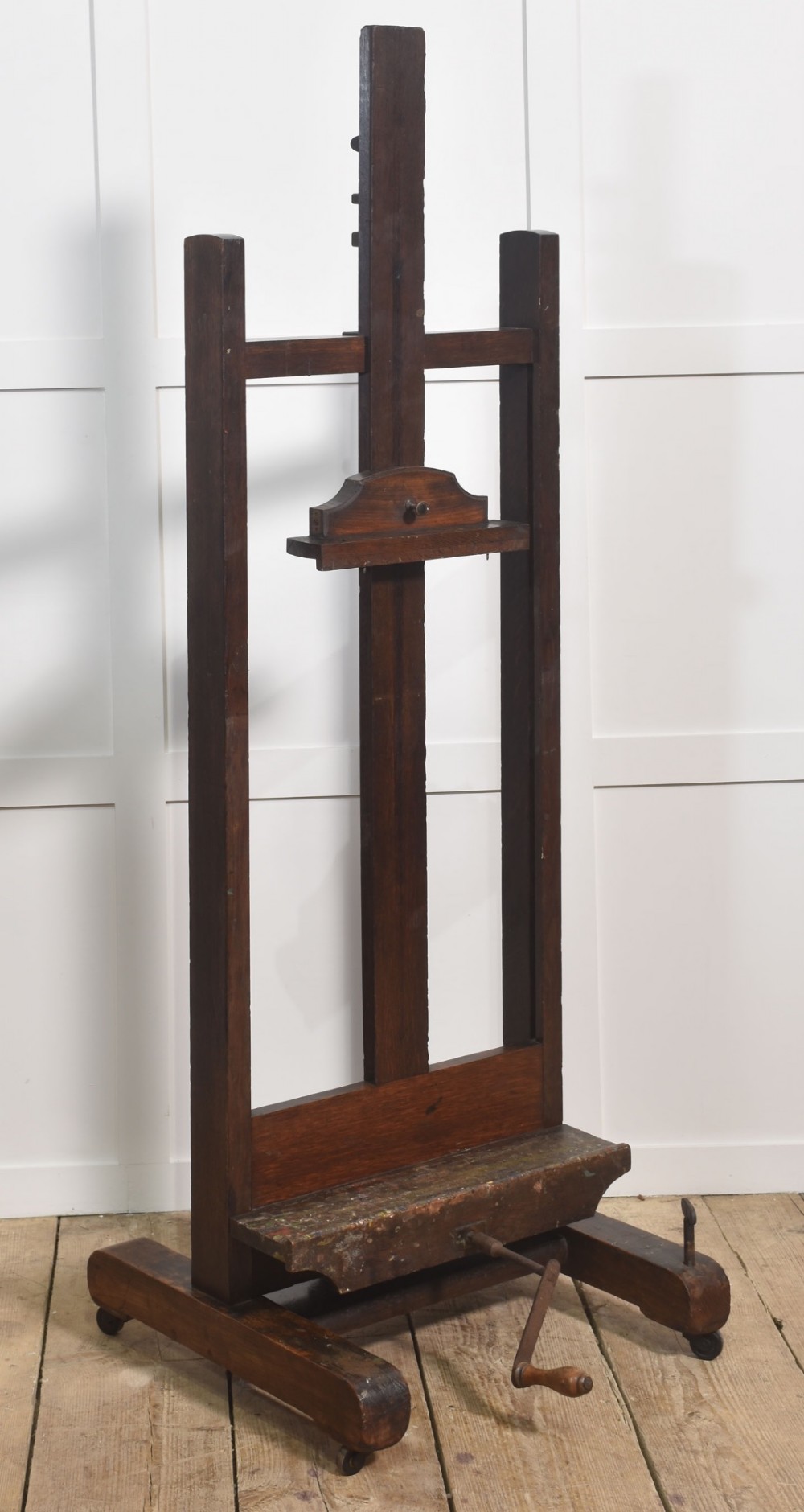 A nineteenth-century dark oak artist studio easel featuring a winding crank handle mechanism and castors on the base.