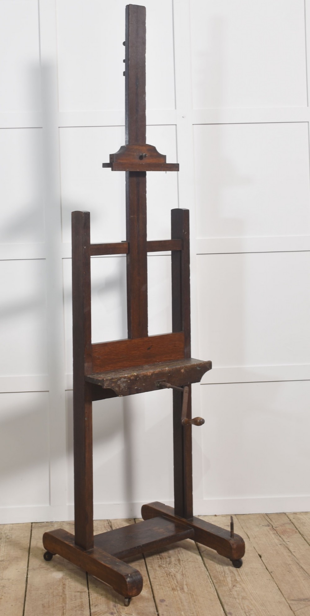 A nineteenth-century dark oak artist studio easel featuring a winding crank handle mechanism and castors on the base. View III