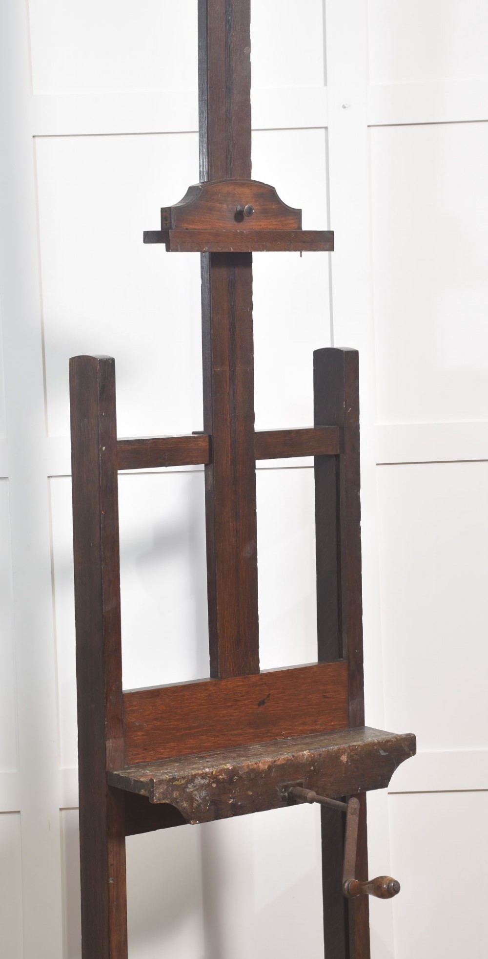 A nineteenth-century dark oak artist studio easel featuring a winding crank handle mechanism and castors on the base. View IV