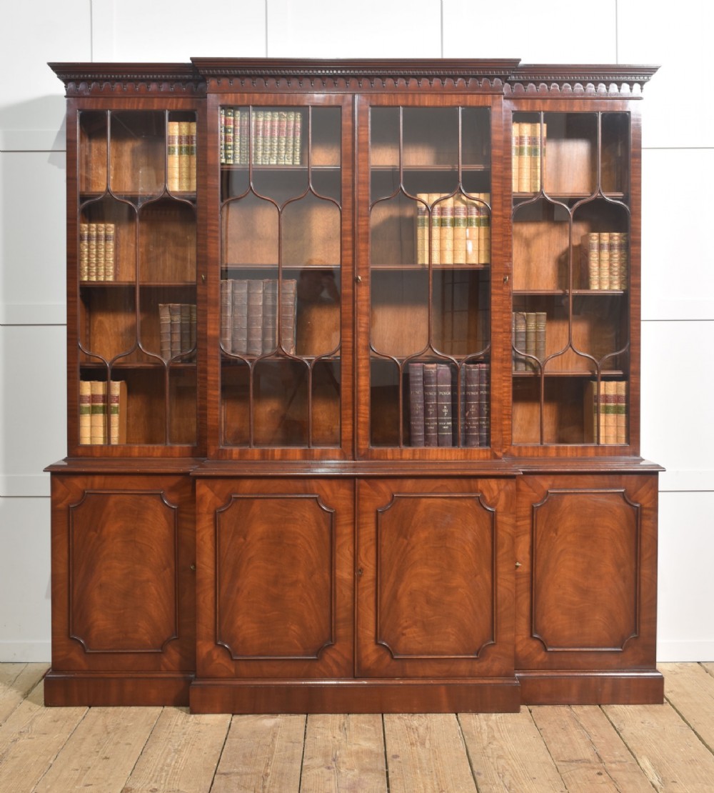 A large Regency Revival flame mahogany breakfront library bookcase with astragal glazed upper doors and panelled cupboard base.