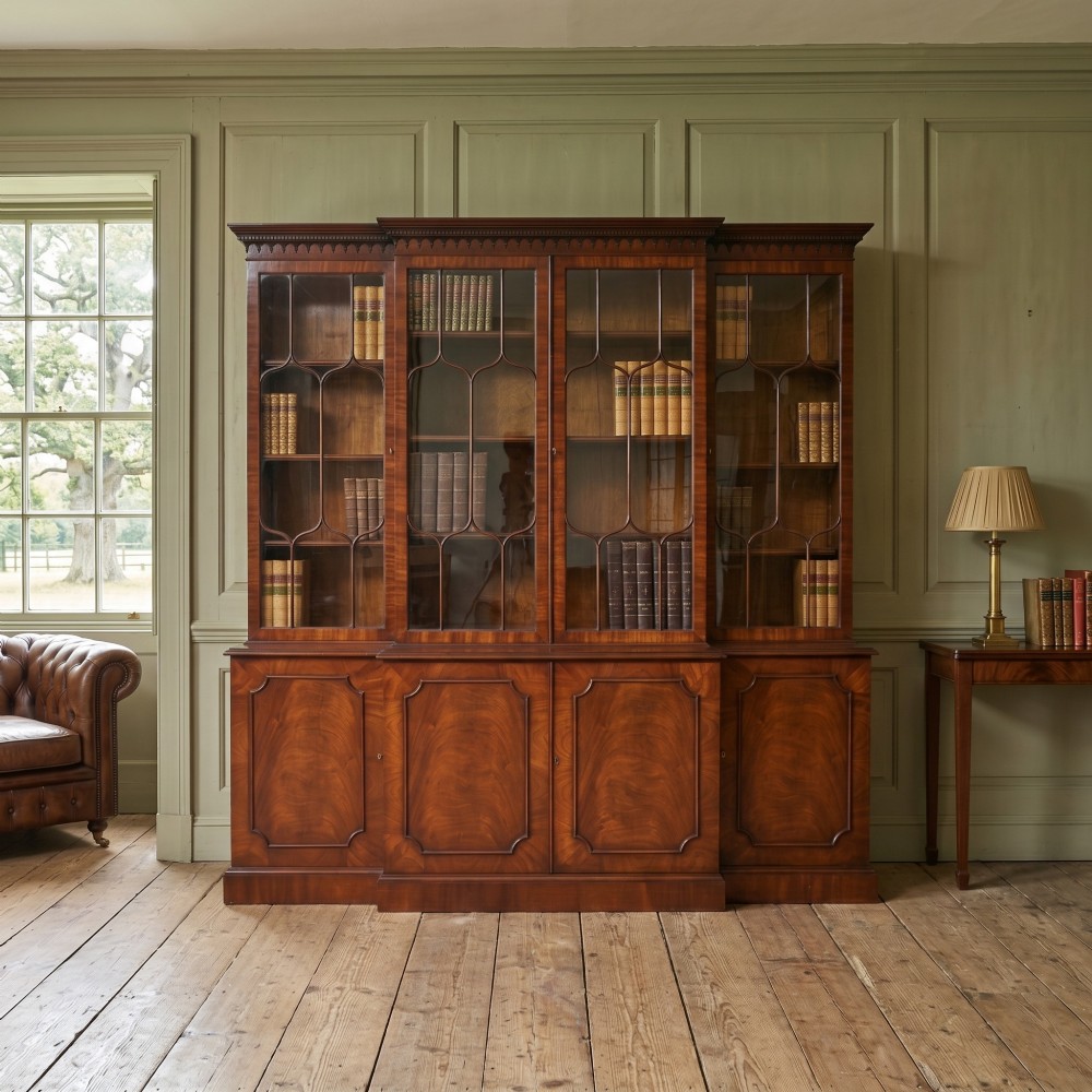 A large Regency Revival flame mahogany breakfront library bookcase with astragal glazed upper doors and panelled cupboard base. View II