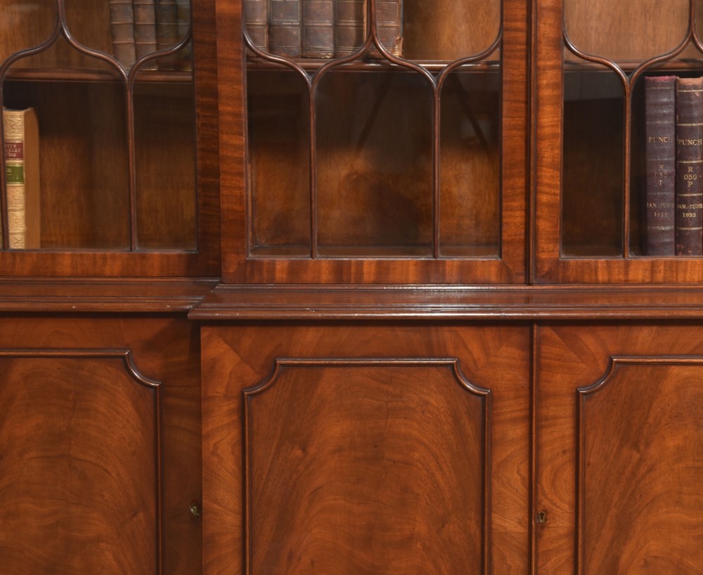 A large Regency Revival flame mahogany breakfront library bookcase with astragal glazed upper doors and panelled cupboard base. View IV