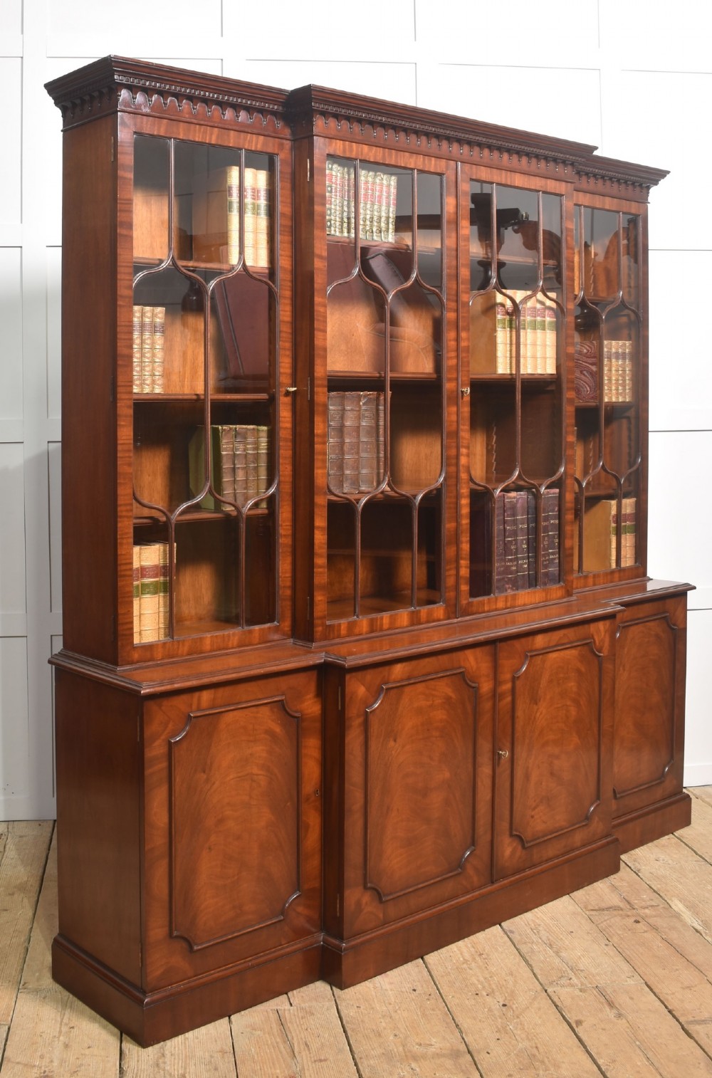 A large Regency Revival flame mahogany breakfront library bookcase with astragal glazed upper doors and panelled cupboard base. View VIII