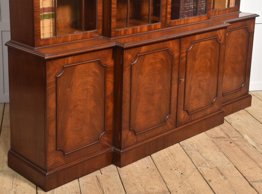 A large Regency Revival flame mahogany breakfront library bookcase with astragal glazed upper doors and panelled cupboard base. View IX
