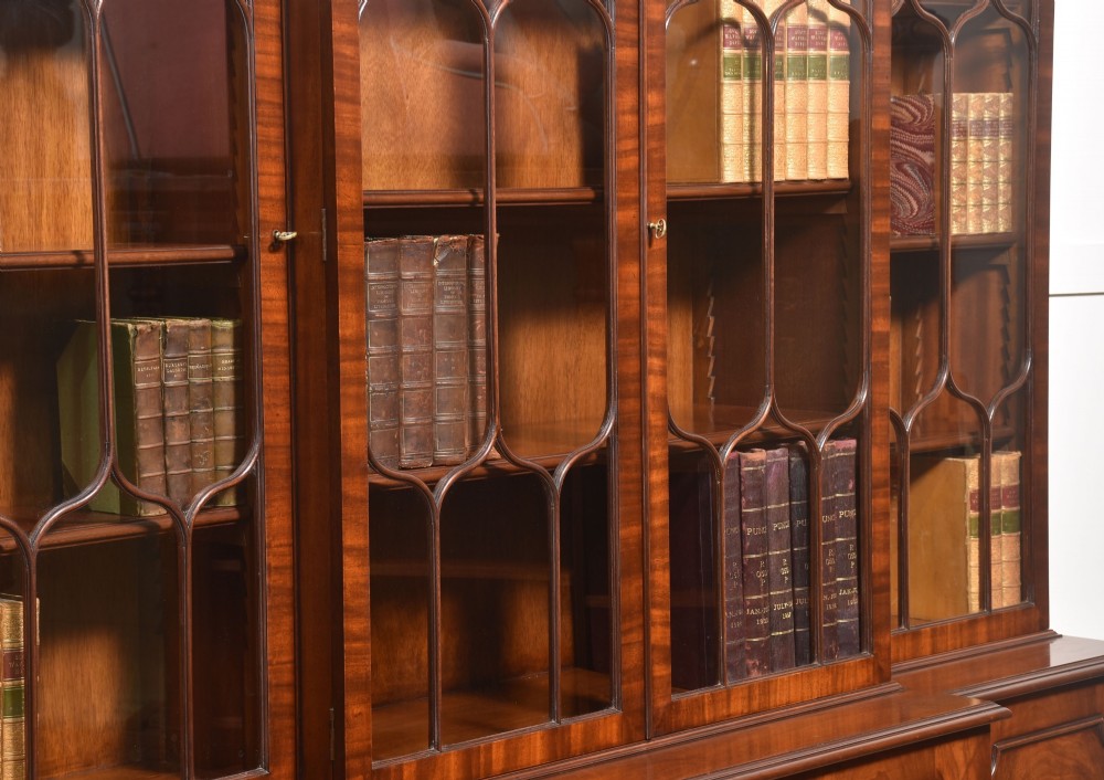 A large Regency Revival flame mahogany breakfront library bookcase with astragal glazed upper doors and panelled cupboard base. View X