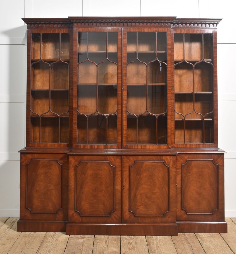 A large Regency Revival flame mahogany breakfront library bookcase with astragal glazed upper doors and panelled cupboard base. View XI