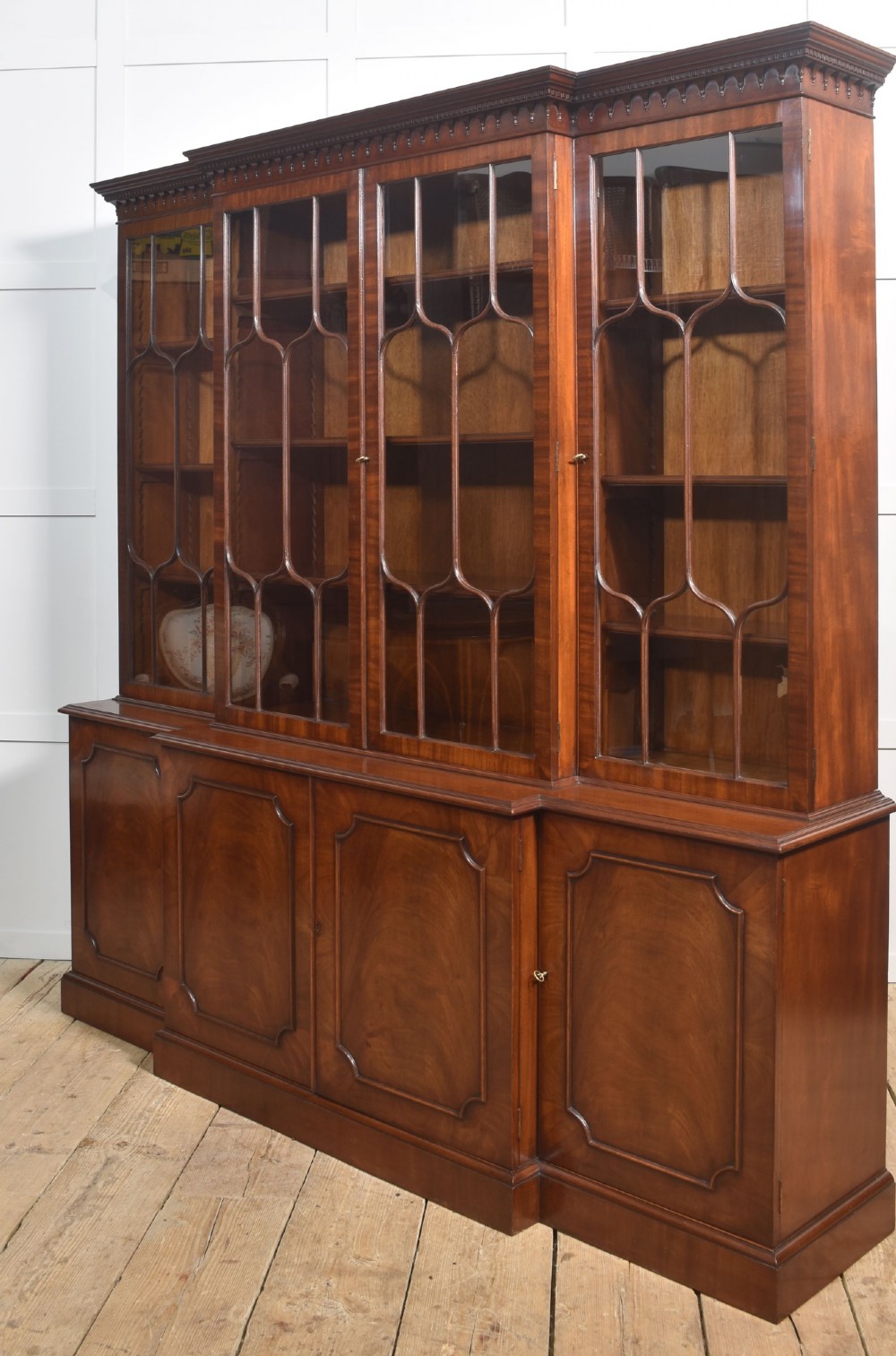 A large Regency Revival flame mahogany breakfront library bookcase with astragal glazed upper doors and panelled cupboard base. View XII