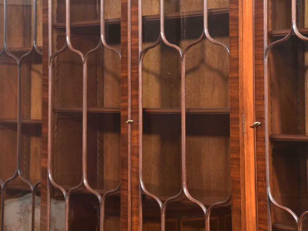 A large Regency Revival flame mahogany breakfront library bookcase with astragal glazed upper doors and panelled cupboard base. View XV
