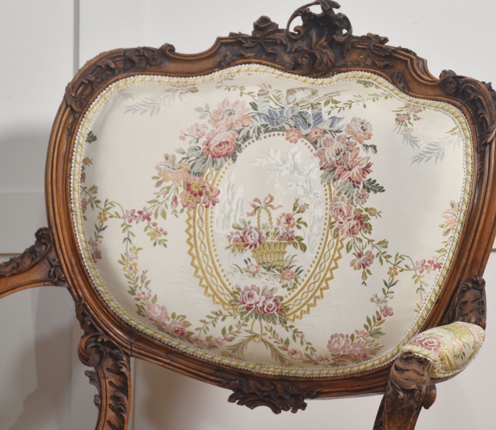 A pair of French carved walnut open armchairs featuring floral tapestry upholstery and cabriole legs. View III