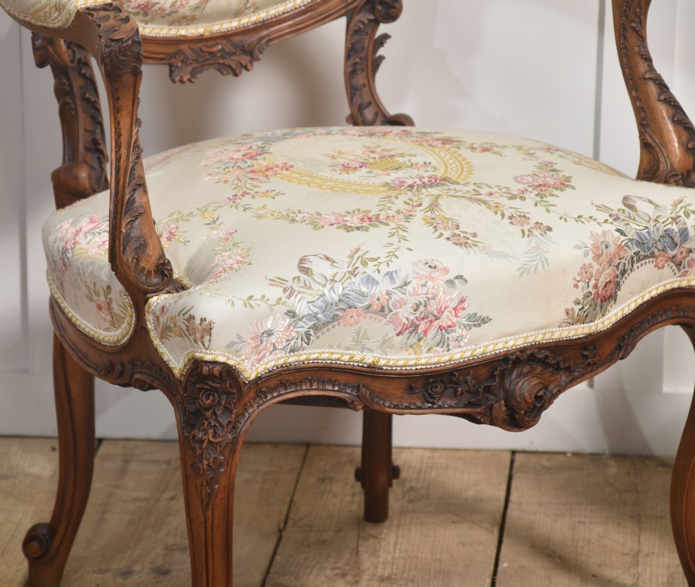 A pair of French carved walnut open armchairs featuring floral tapestry upholstery and cabriole legs. View IV