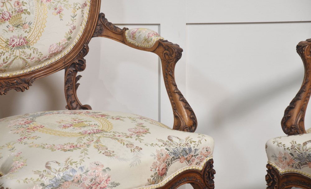 A pair of French carved walnut open armchairs featuring floral tapestry upholstery and cabriole legs. View V