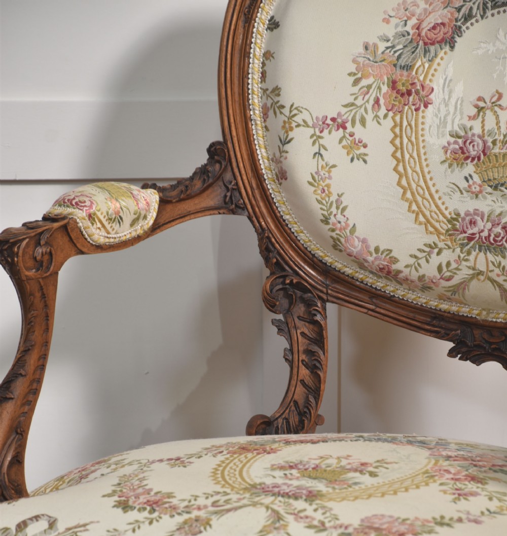 A pair of French carved walnut open armchairs featuring floral tapestry upholstery and cabriole legs. View VI