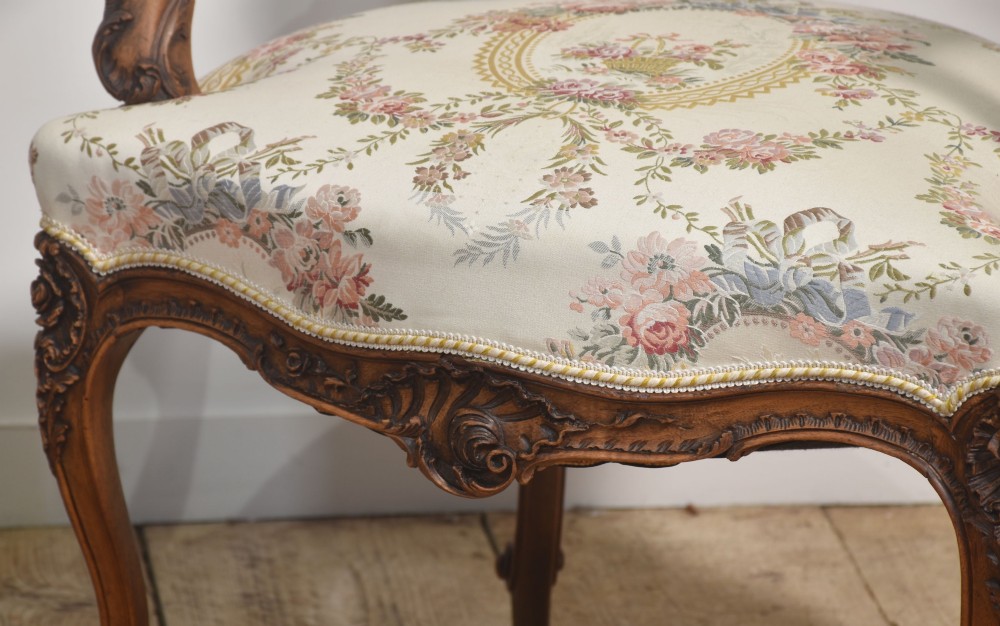 A pair of French carved walnut open armchairs featuring floral tapestry upholstery and cabriole legs. View VIII