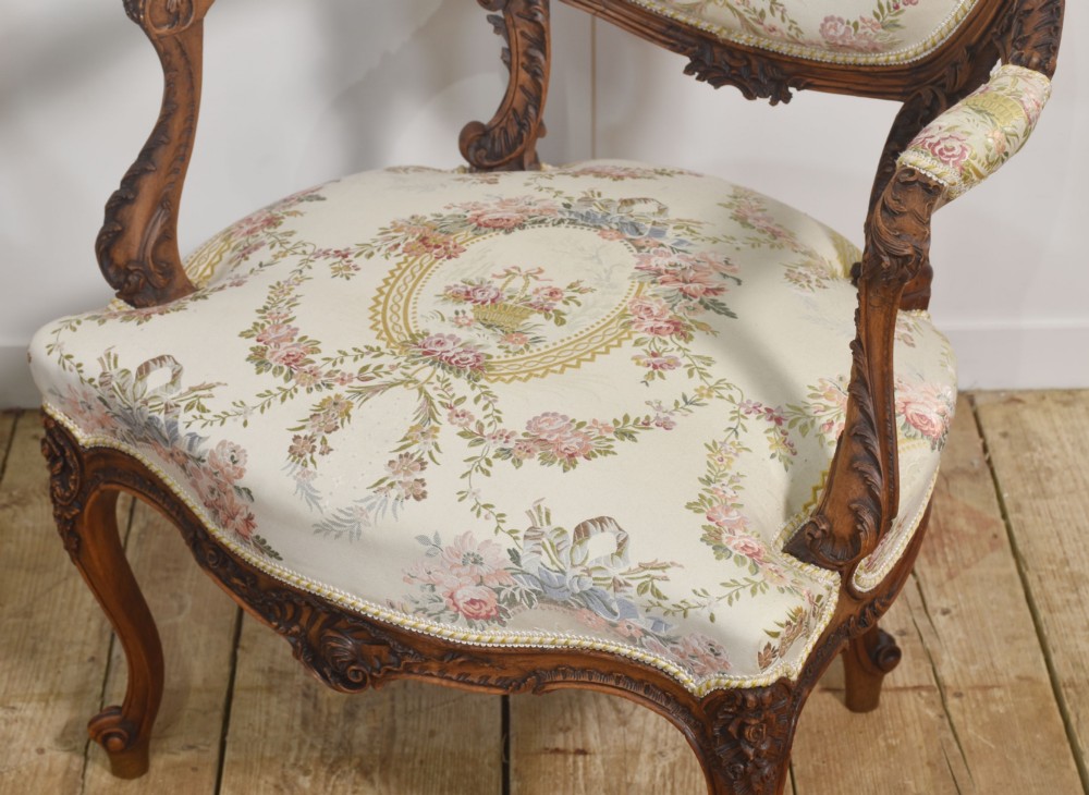 A pair of French carved walnut open armchairs featuring floral tapestry upholstery and cabriole legs. View X