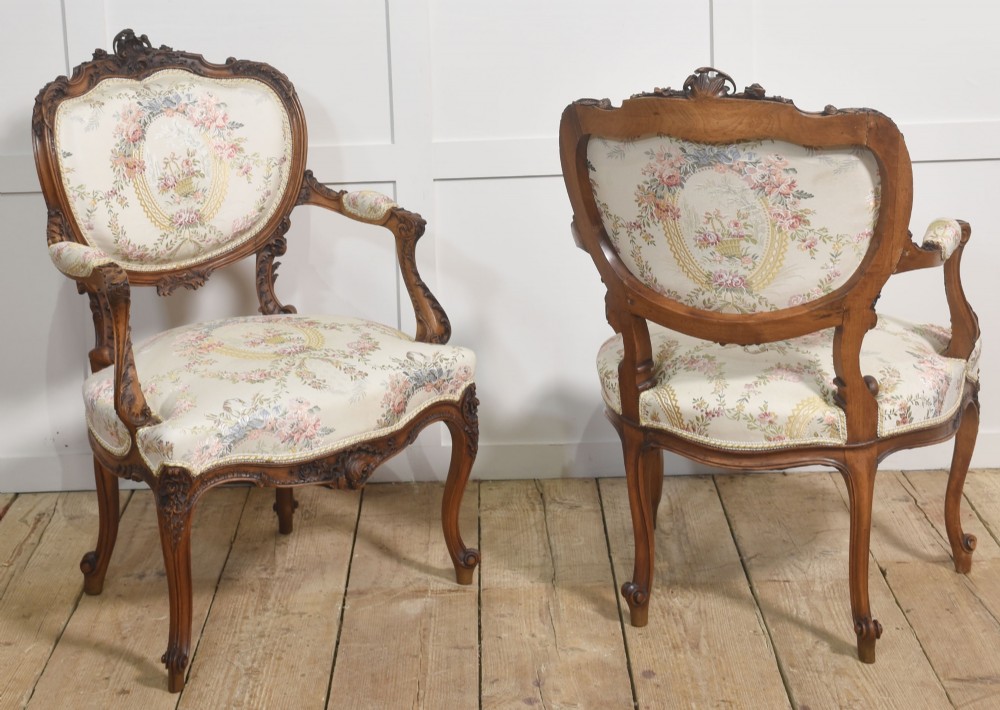 A pair of French carved walnut open armchairs featuring floral tapestry upholstery and cabriole legs. View XII
