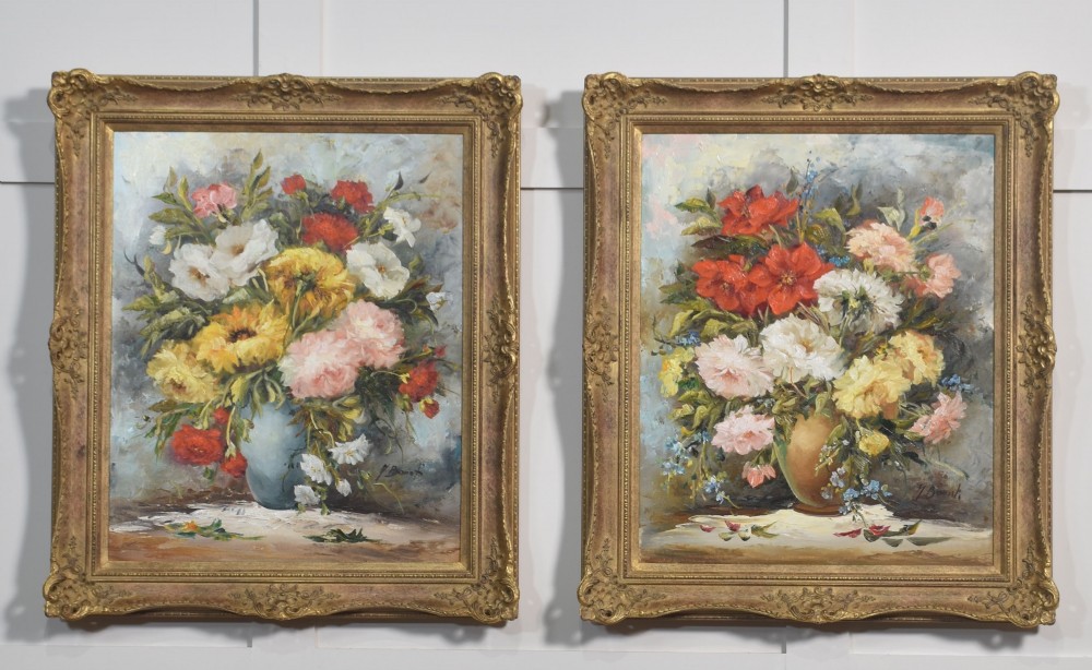 A pair of framed oil paintings depicting colourful arrangements of flowers in ceramic vases set within ornate gilded frames.