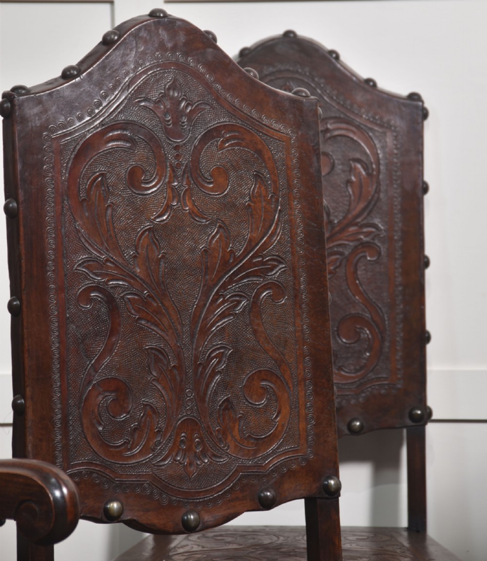 A set of eight dark brown walnut dining chairs featuring embossed floral leather seats and backrests with decorative studding and barley twist legs. View III