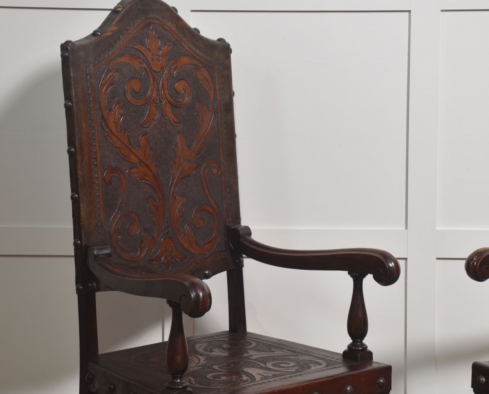 A set of eight dark brown walnut dining chairs featuring embossed floral leather seats and backrests with decorative studding and barley twist legs. View V