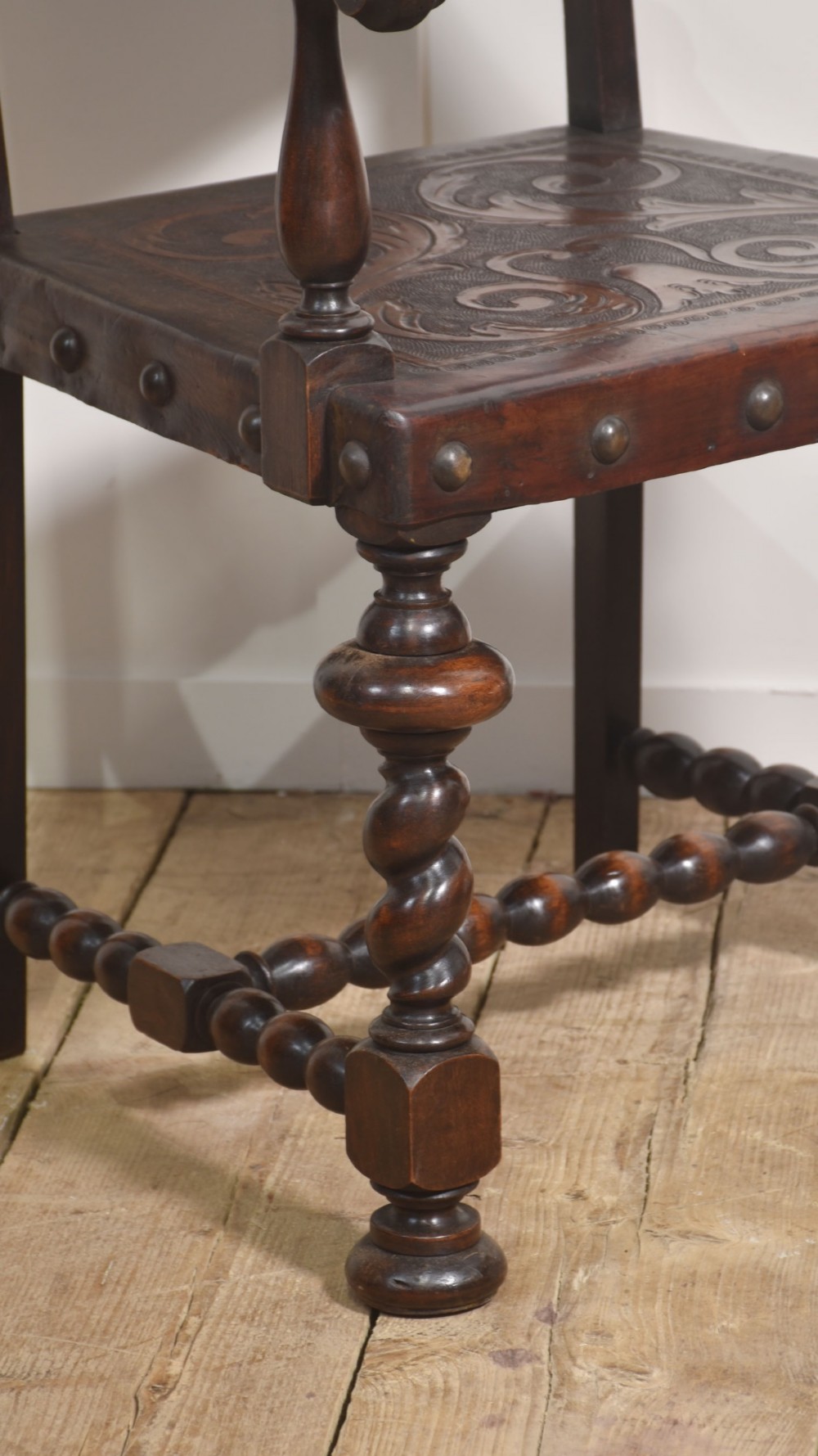 A set of eight dark brown walnut dining chairs featuring embossed floral leather seats and backrests with decorative studding and barley twist legs. View VI
