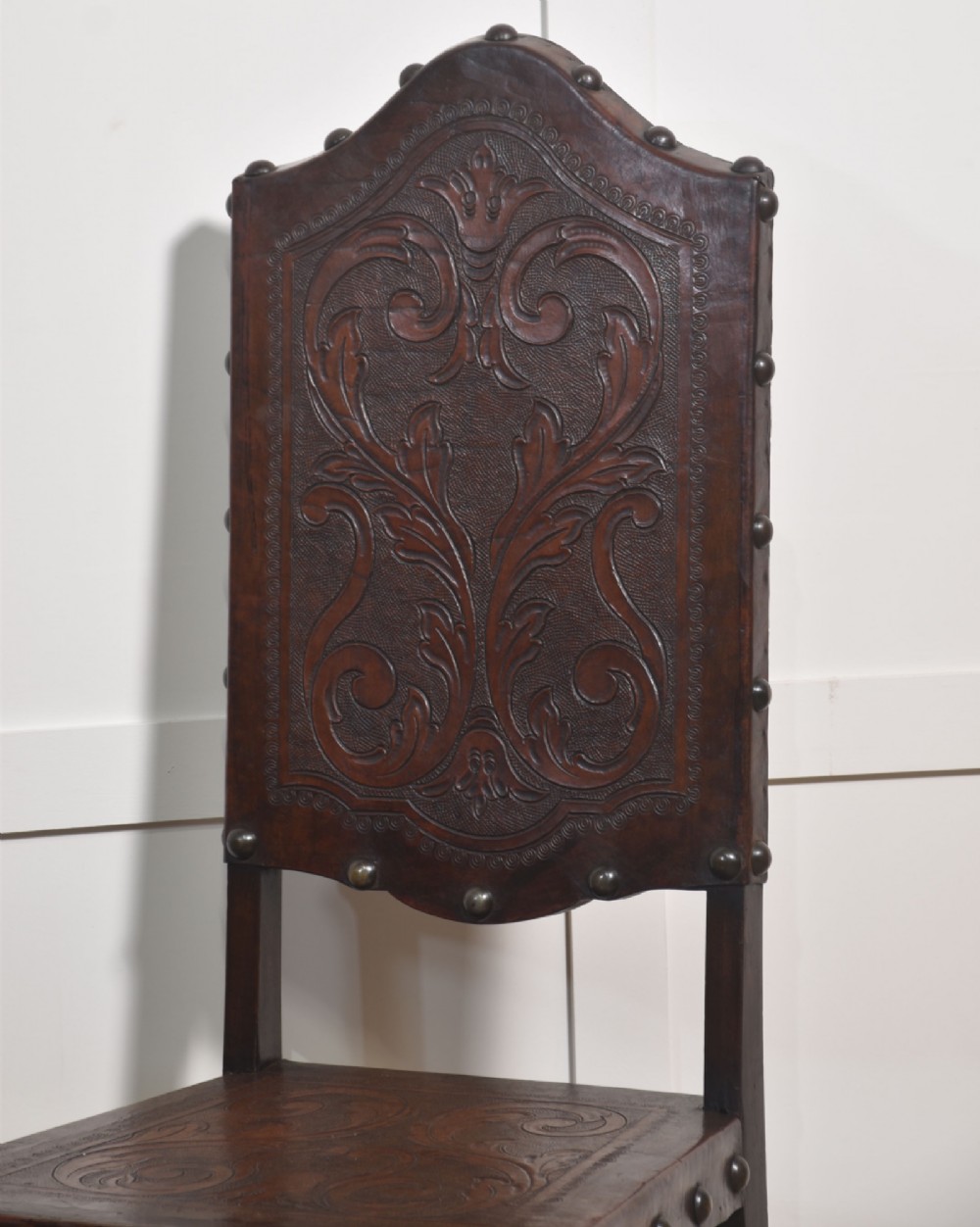 A set of eight dark brown walnut dining chairs featuring embossed floral leather seats and backrests with decorative studding and barley twist legs. View IX
