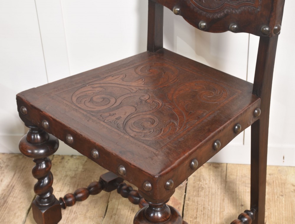 A set of eight dark brown walnut dining chairs featuring embossed floral leather seats and backrests with decorative studding and barley twist legs. View X