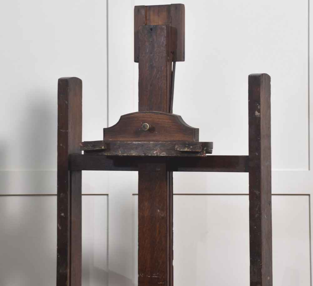 A dark oak adjustable artist studio easel featuring a hand-crank winding mechanism and a castored base. View IV