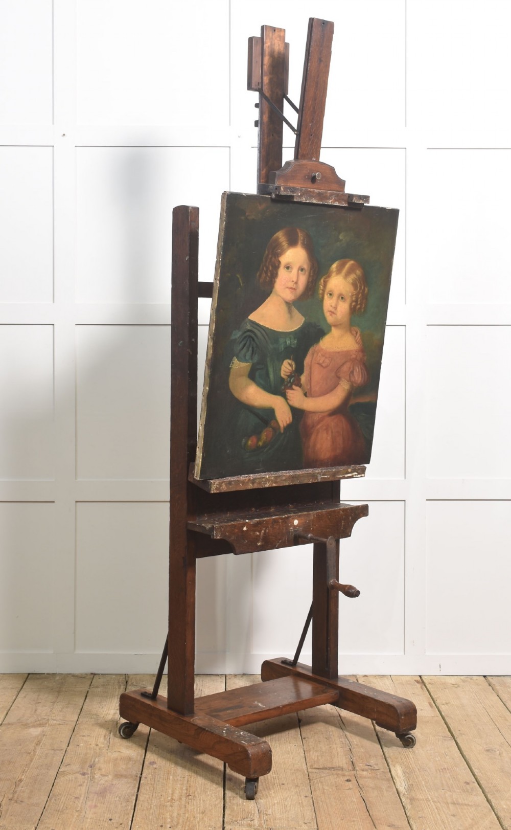 A dark oak adjustable artist studio easel featuring a hand-crank winding mechanism and a castored base. View VII