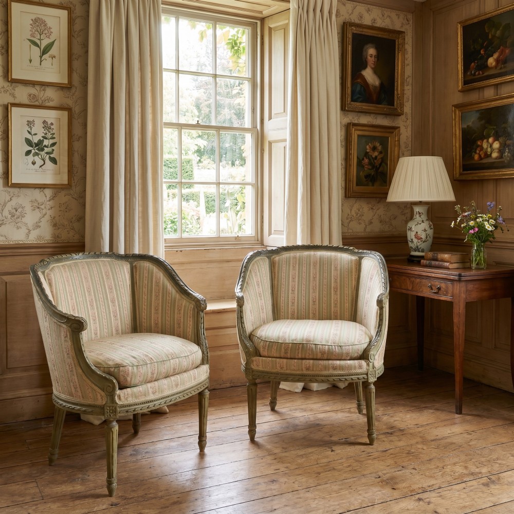 A pair of grey-painted French tub armchairs upholstered in a striped floral pastel fabric with fluted legs. View II
