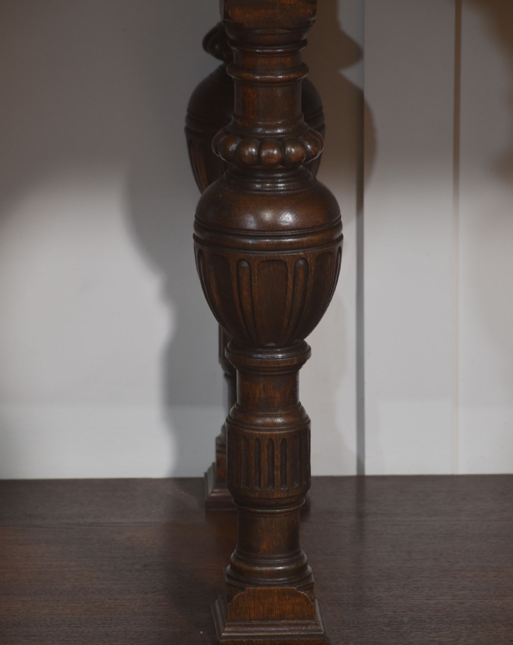 A dark oak Jacobean style dresser base featuring three drawers with decorative brass handles, turned baluster legs, and a full-length lower pot board shelf. View III