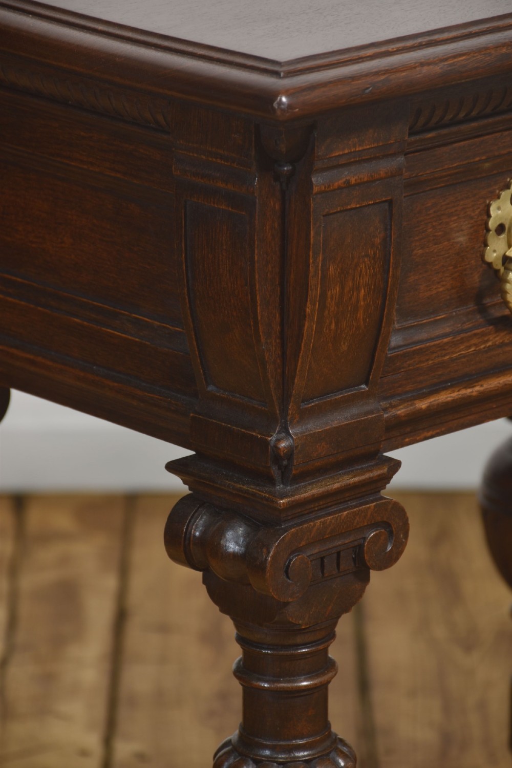 A dark oak Jacobean style dresser base featuring three drawers with decorative brass handles, turned baluster legs, and a full-length lower pot board shelf. View IV