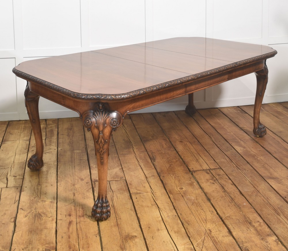 A carved walnut extending dining table resting on four cabriole legs with carved knees and claw and ball feet.