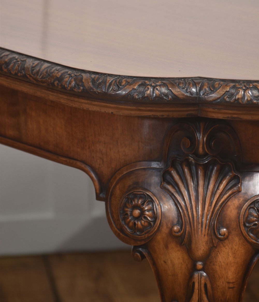A carved walnut extending dining table resting on four cabriole legs with carved knees and claw and ball feet. View VI