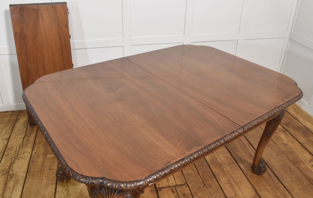 A carved walnut extending dining table resting on four cabriole legs with carved knees and claw and ball feet. View X