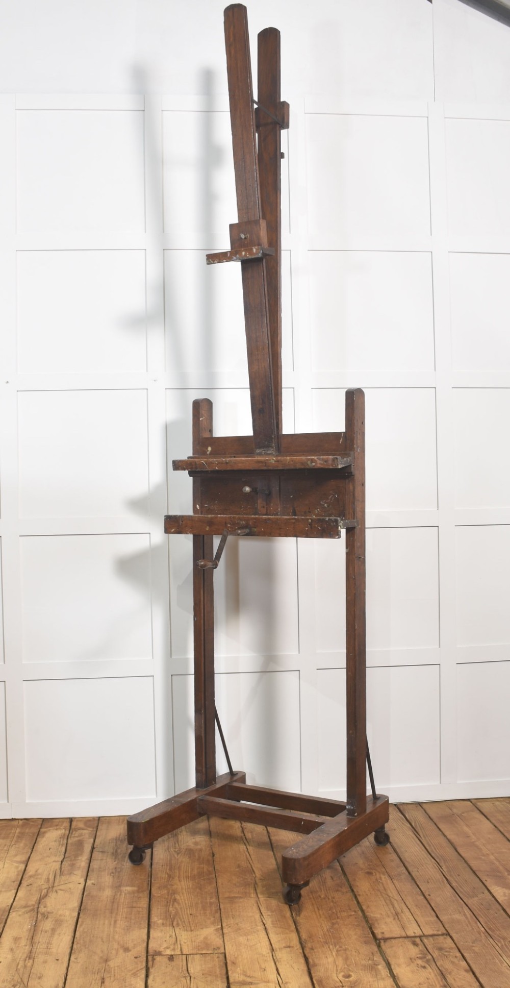 A late nineteenth-century dark oak artist studio easel featuring an adjustable central shaft, crank handle, and cast iron castors on an H-frame base. View III
