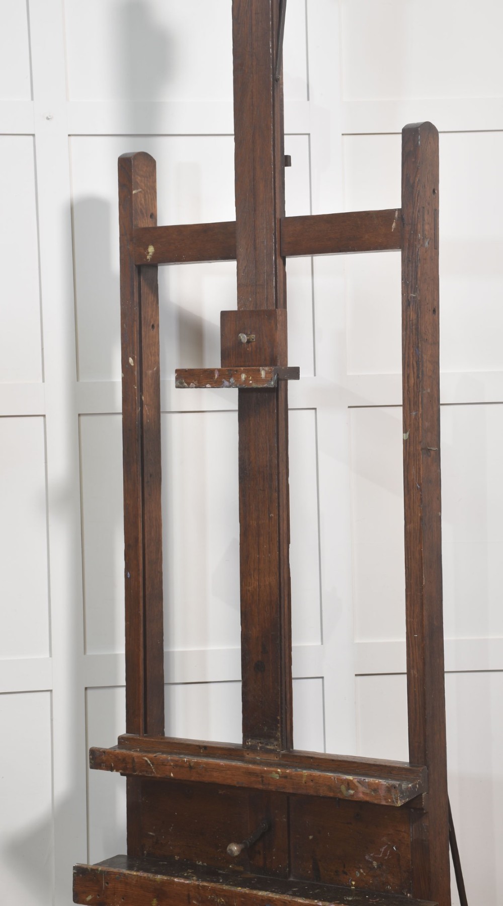 A late nineteenth-century dark oak artist studio easel featuring an adjustable central shaft, crank handle, and cast iron castors on an H-frame base. View XIV